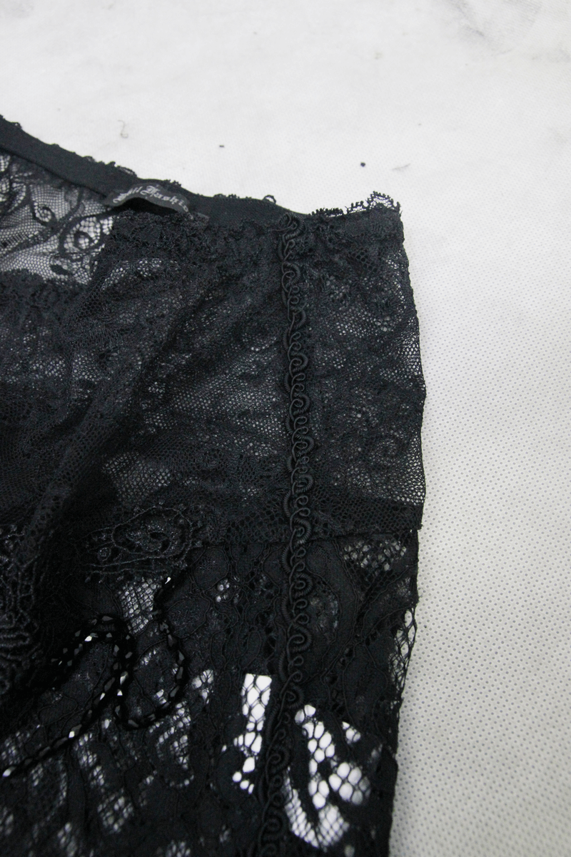 Close-up of gothic black lace fabric showcasing intricate details and transparent design for stylish women's trousers.