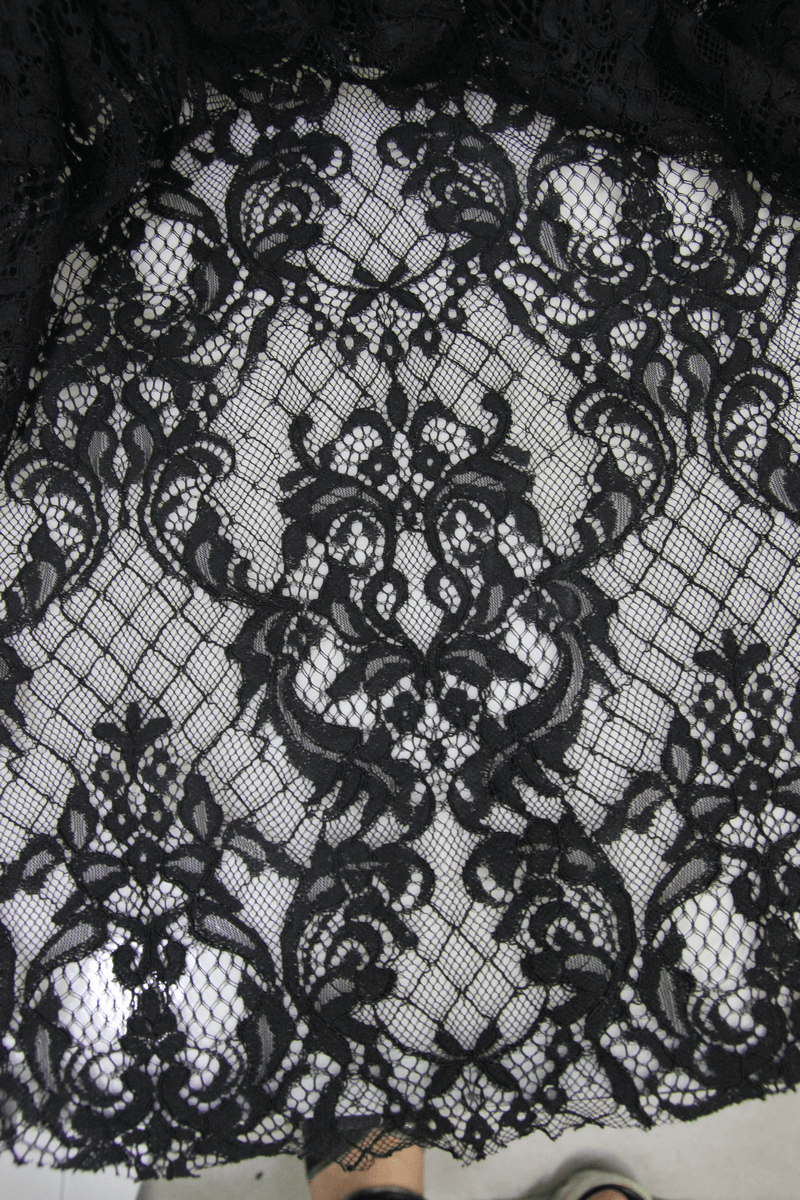 Close-up of intricate black lace fabric perfect for gothic style pants, showcasing floral patterns and transparency.