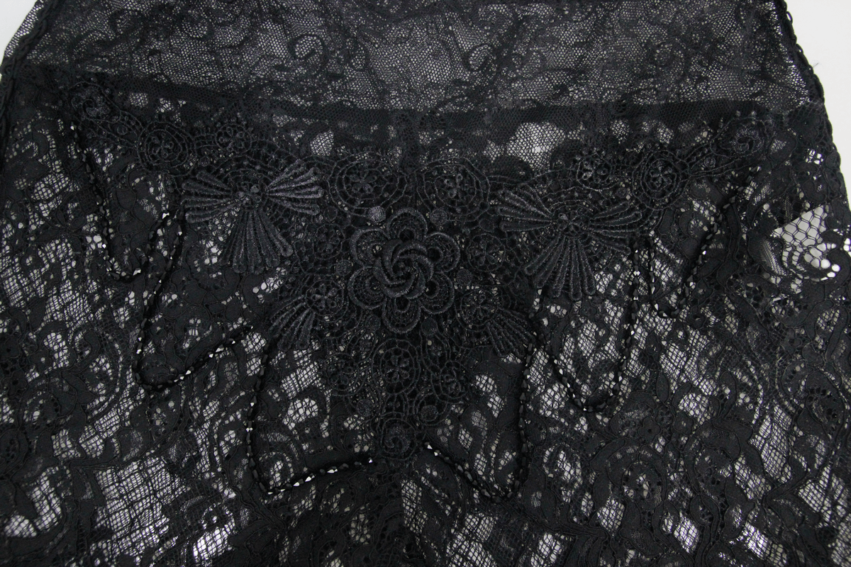 Detailed close-up of black lace fabric featuring intricate floral patterns, showcasing gothic style elegance.