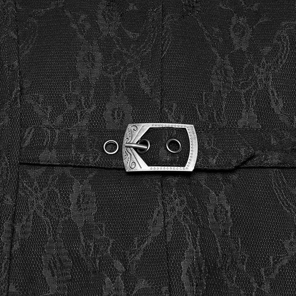 Close-up of engraved silver button detail on a gothic black lace waistcoat, showcasing intricate floral pattern.