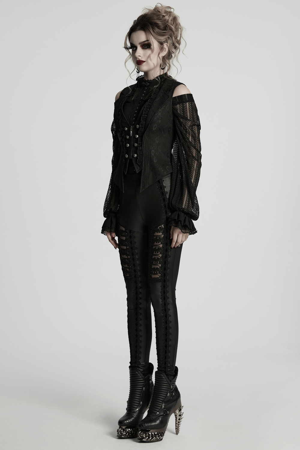 Gothic model in black lace waistcoat, ruffled blouse, and stylish high-heeled boots for edgy fashion inspiration.