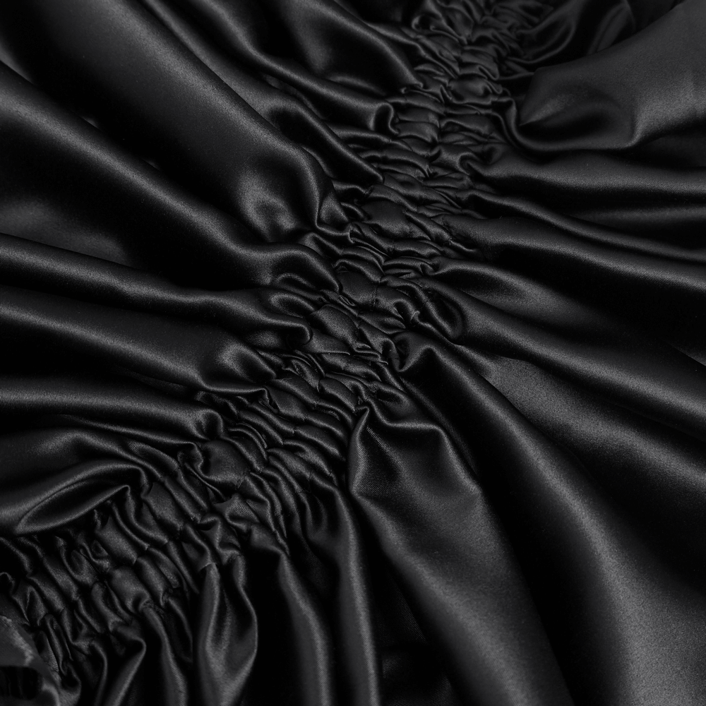 Close-up of elegant black satin fabric showcasing soft ruffles and intricate stitching detail.