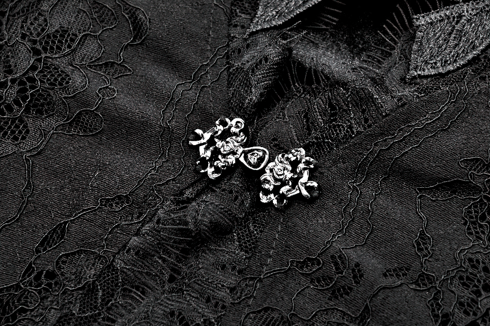 Close-up of intricate black lace with elegant silver floral embellishments, perfect for gothic fashion.