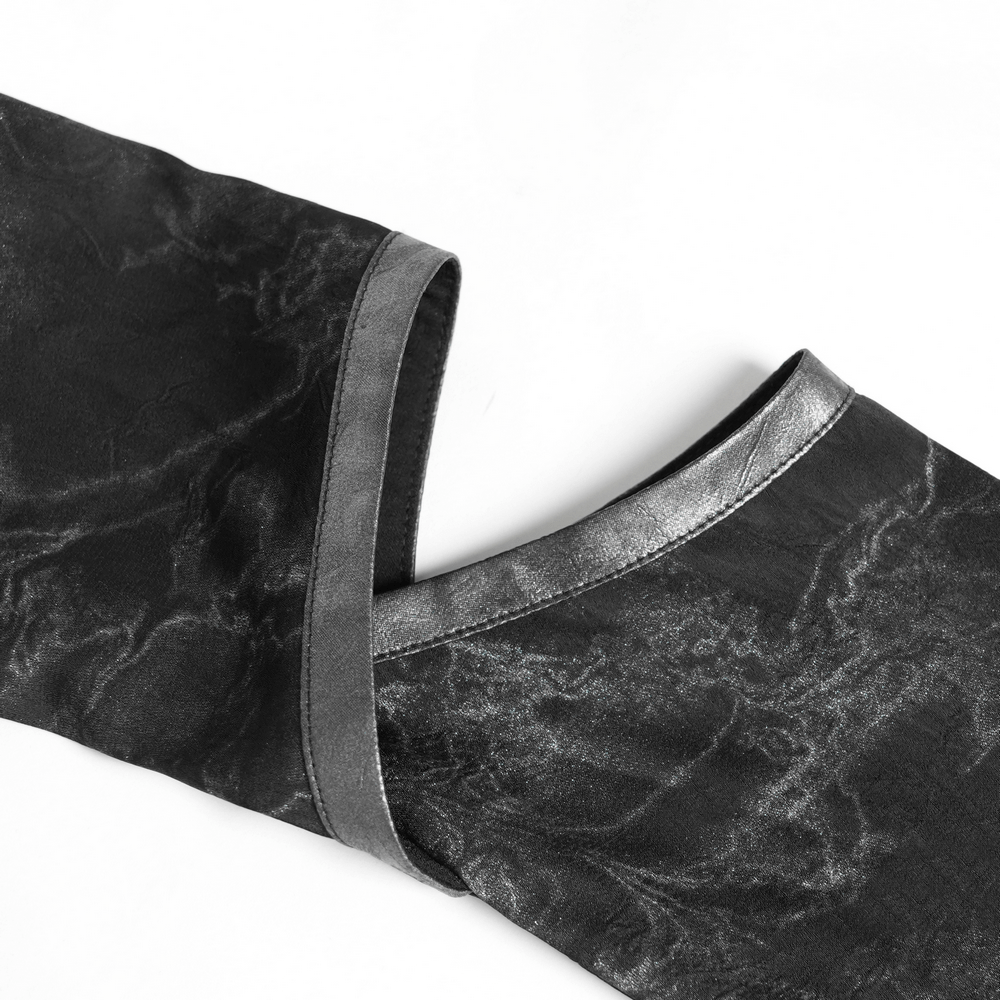 Close-up of gothic black lace-up shirt sleeve with cut-out design and metallic trim.