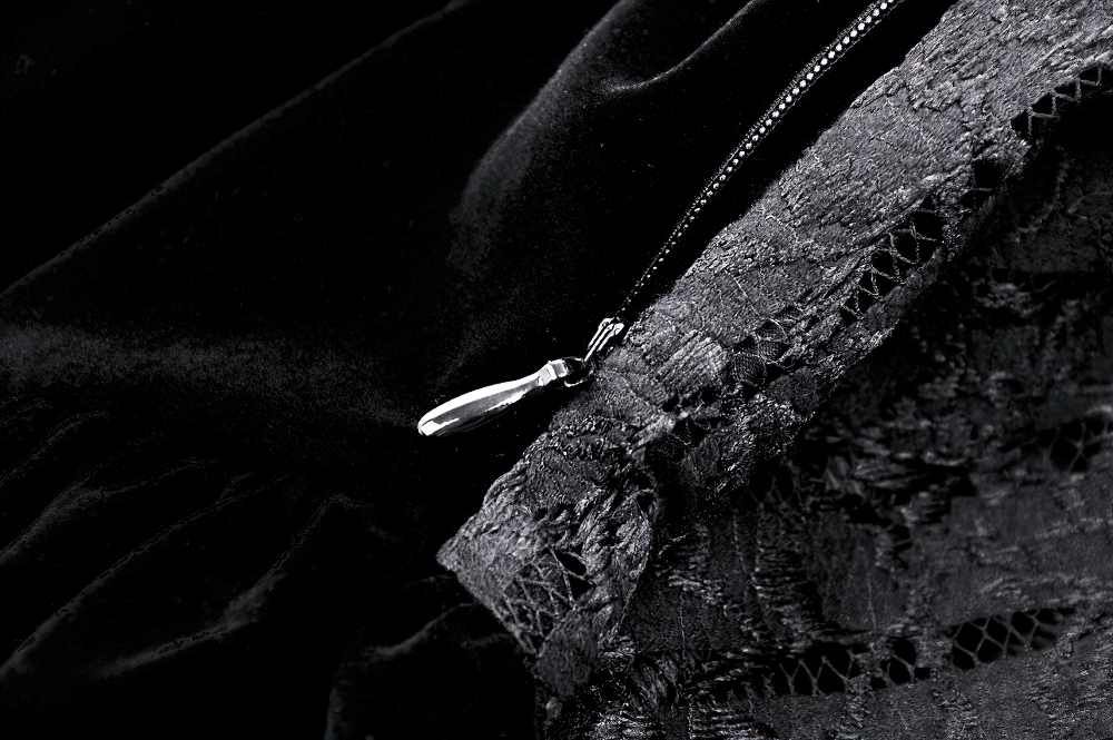 Close-up of intricate black lace and velvet fabric with delicate button detail, perfect for gothic elegance.