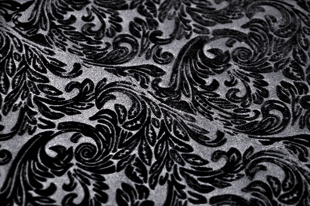 Ornate black lace pattern on velvet fabric, exuding gothic elegance and vintage Victorian charm.