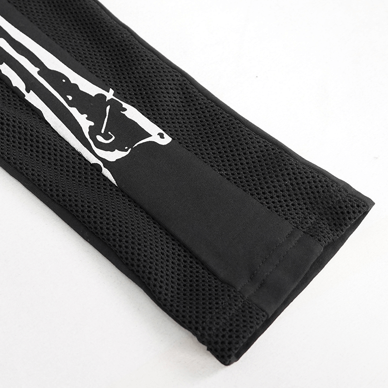 Close-up of gothic black leggings featuring a white skeleton pattern, showcasing stylish fabric and mesh details.