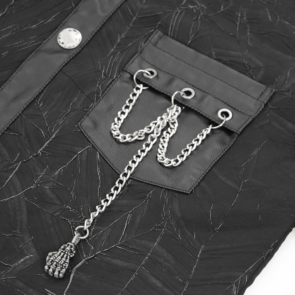 Close-up of Gothic black shirt pocket with silver chains and skull pendant, featuring leather accents and unique texture.