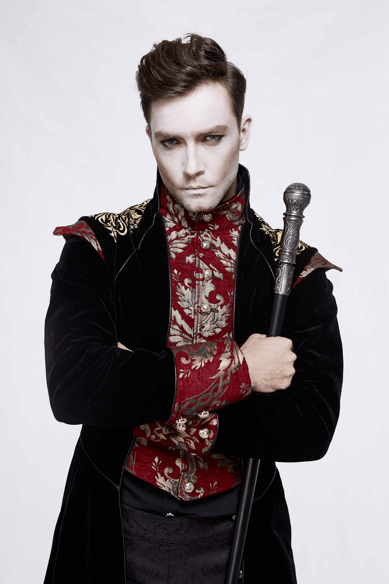 Stylish man in a gothic black long tail coat with vintage pattern, holding a staff, embodying dark elegance.