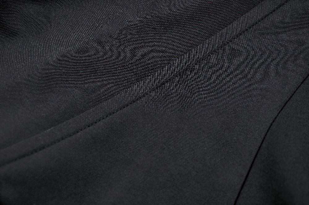 Close-up of sleek black fabric showcasing textured patterns of a gothic masked hooded cape.