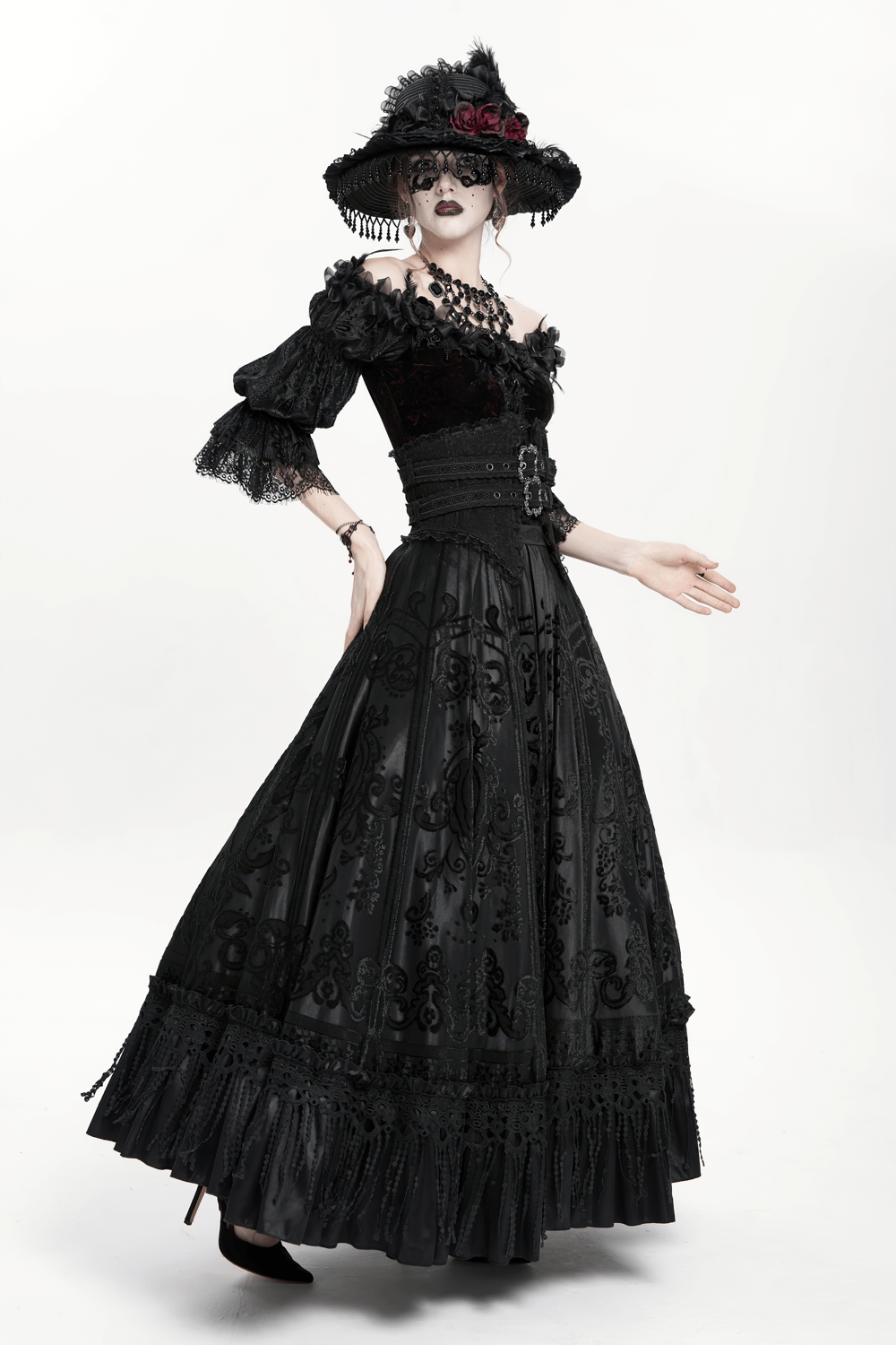 Gothic black maxi skirt with lace overlay and corset waist, paired with a wide-brimmed hat and striking accessories.