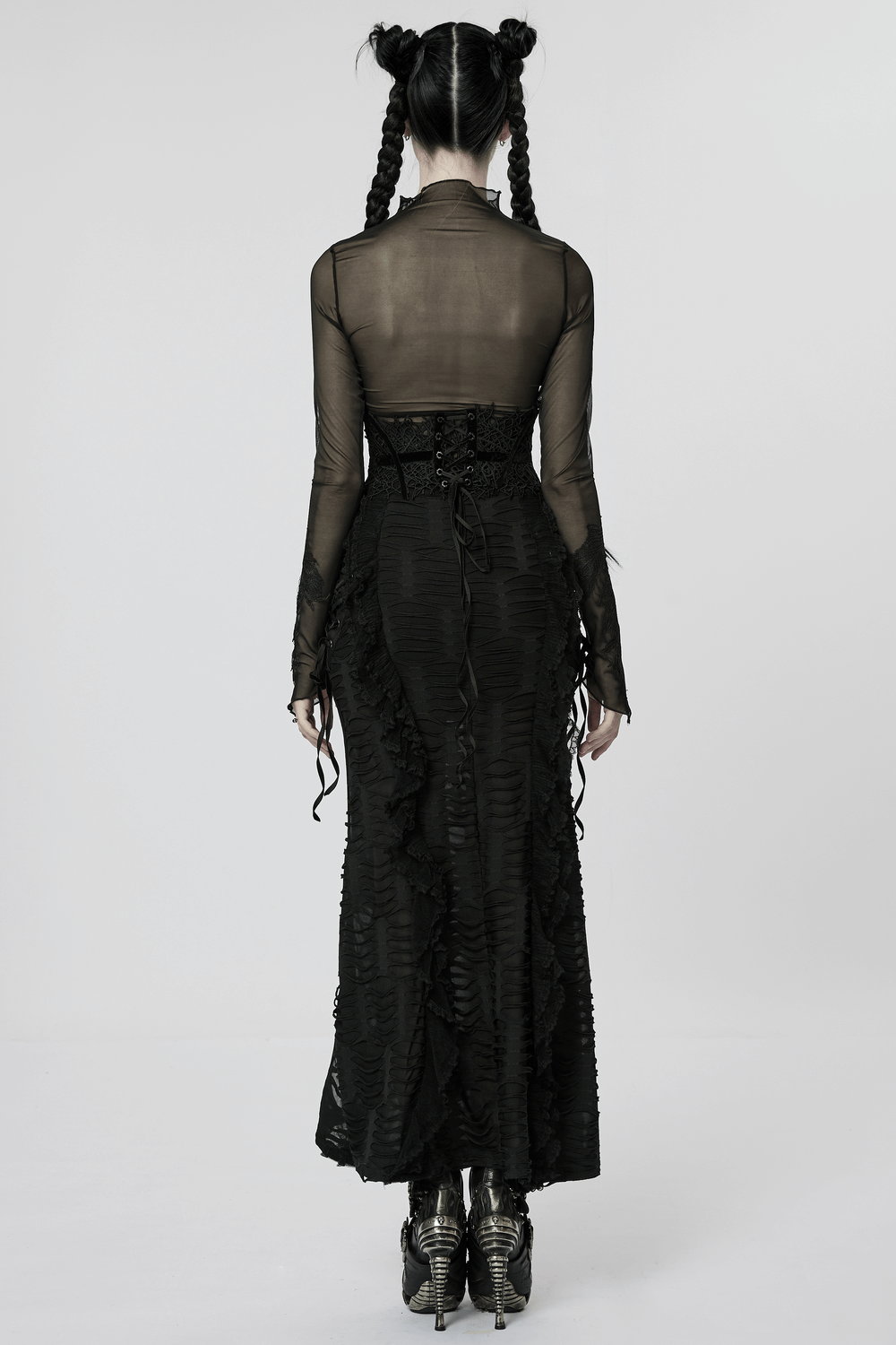 Back view of a woman in a gothic sheer black dress with corset belt, accentuated by textured layers and stylish boots.