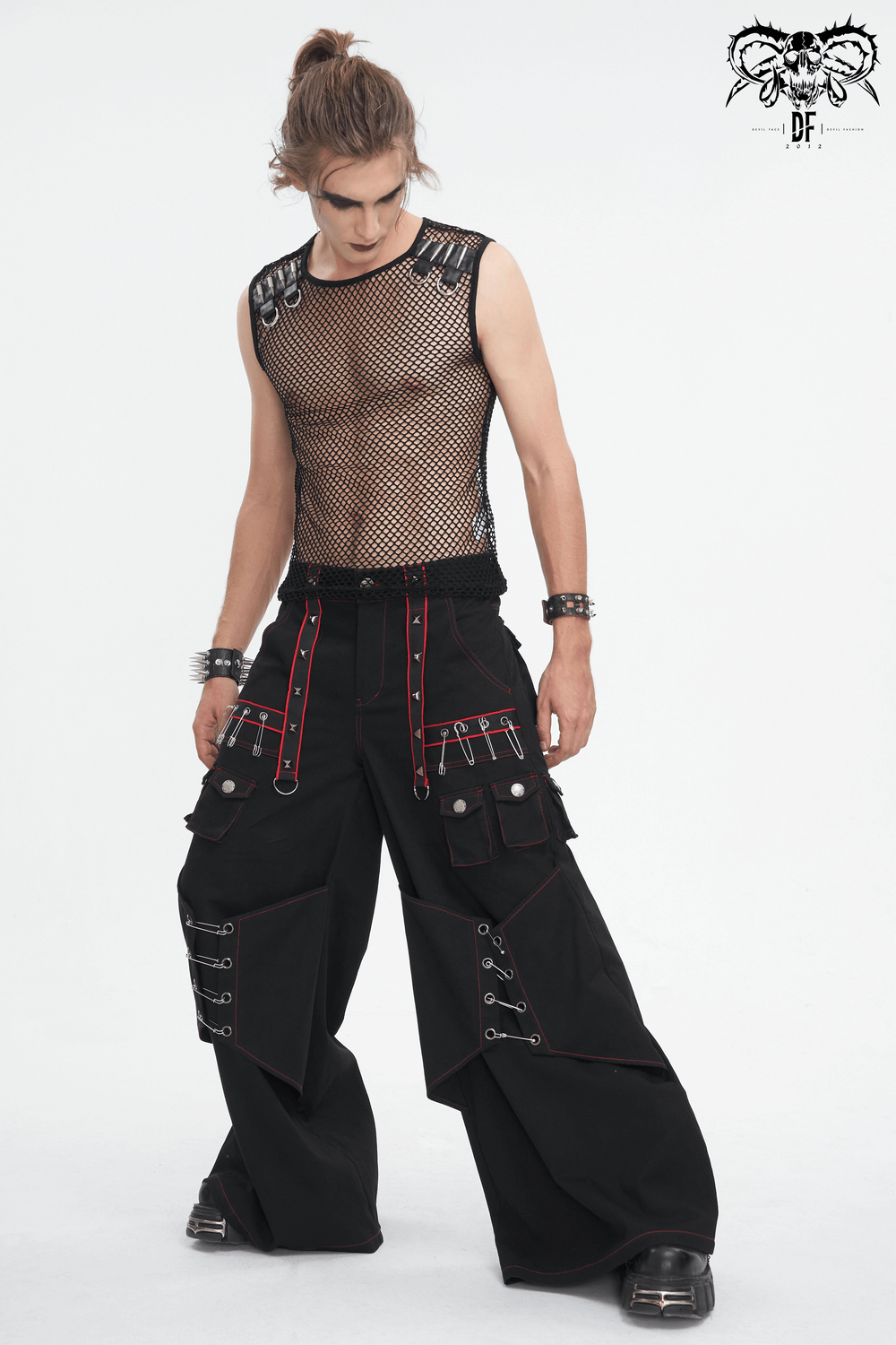 Gothic black pants with red stitching and metal accents, styled with a mesh top for an edgy, fashion-forward look.