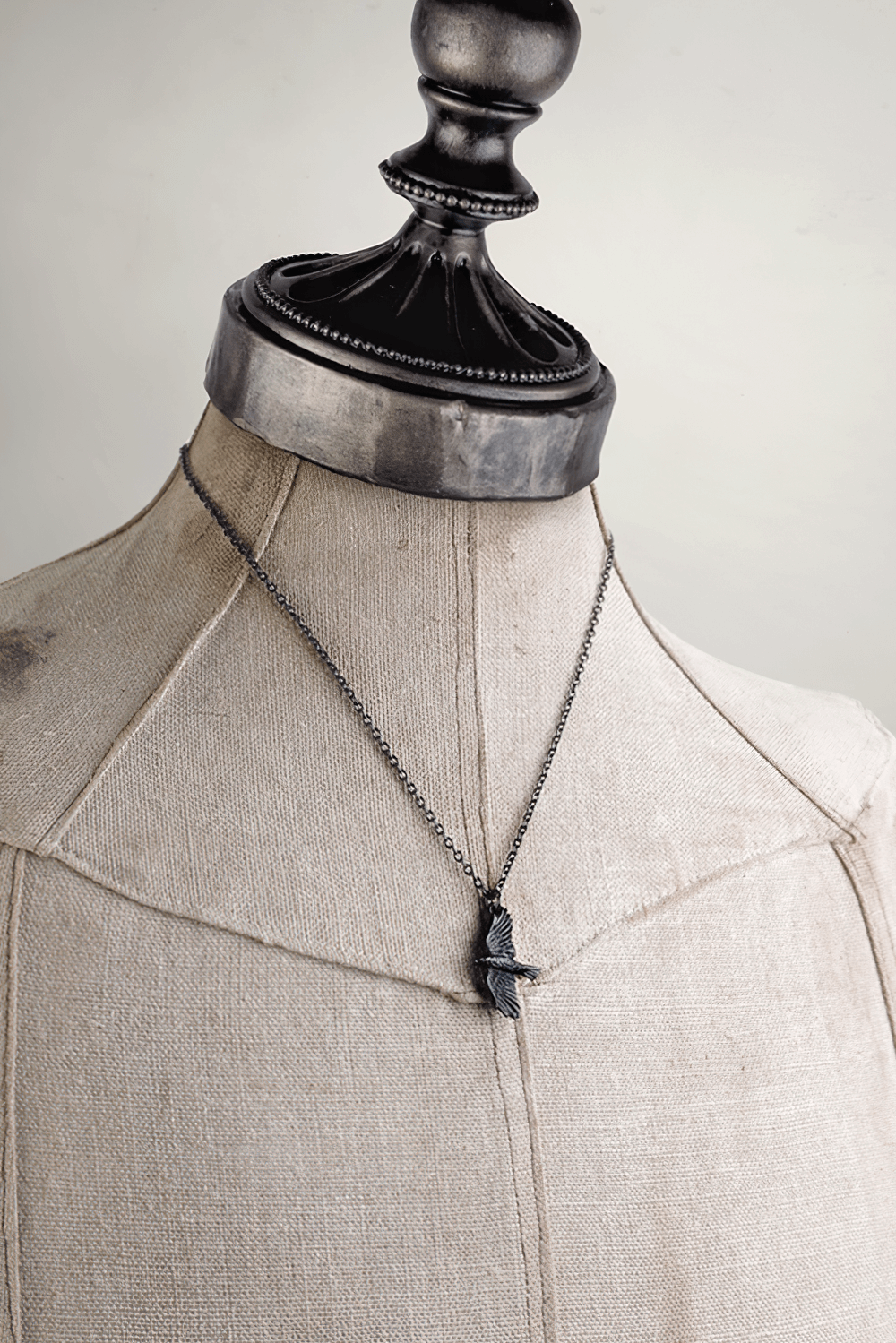 Gothic black raven pendant necklace on a dress form, inspired by Norse mythology and symbolism.