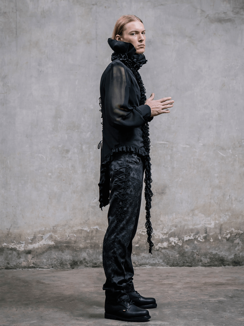 Model showcasing Gothic black silk high waist trousers with vintage print and edgy style against a textured wall.