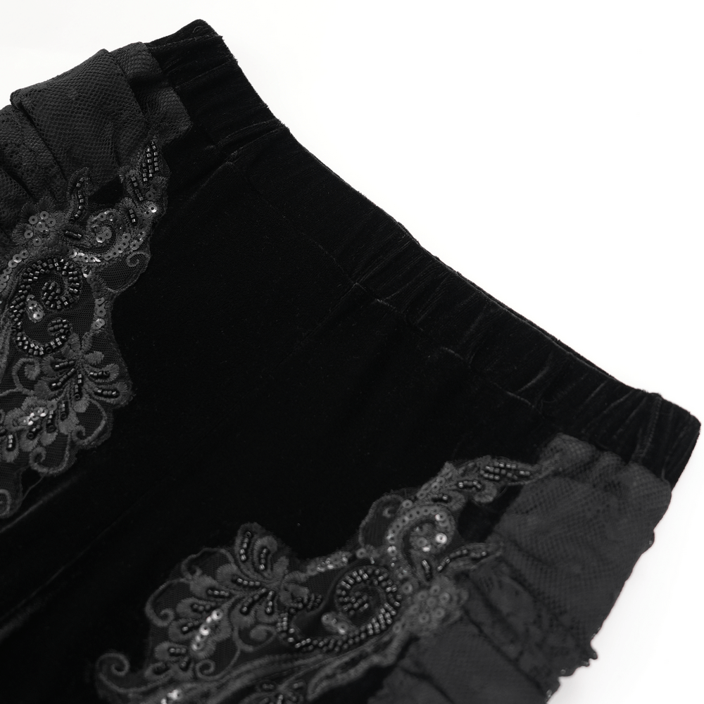 Close-up of gothic black velvet pants with ornate baroque lace embroidery and stretchy waistband.