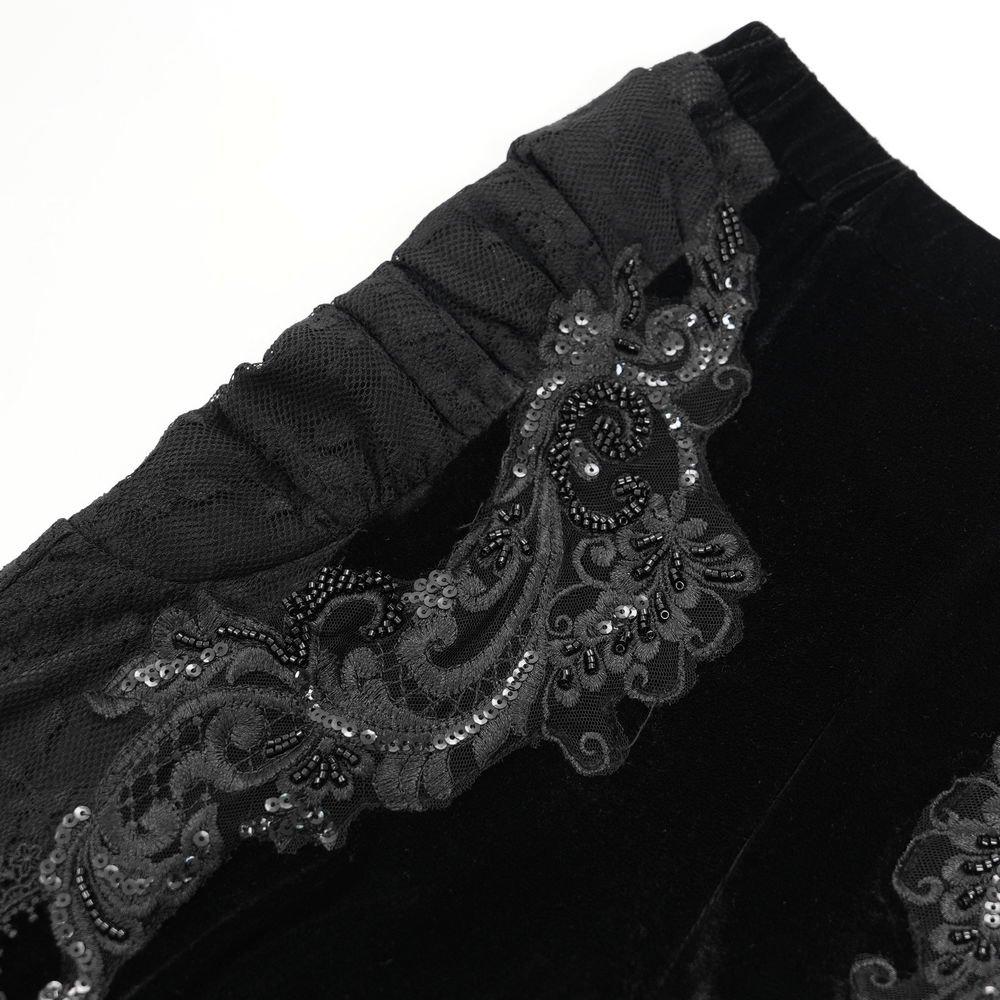 Close-up of gothic black velvet pants with intricate baroque lace and embroidery detailing.