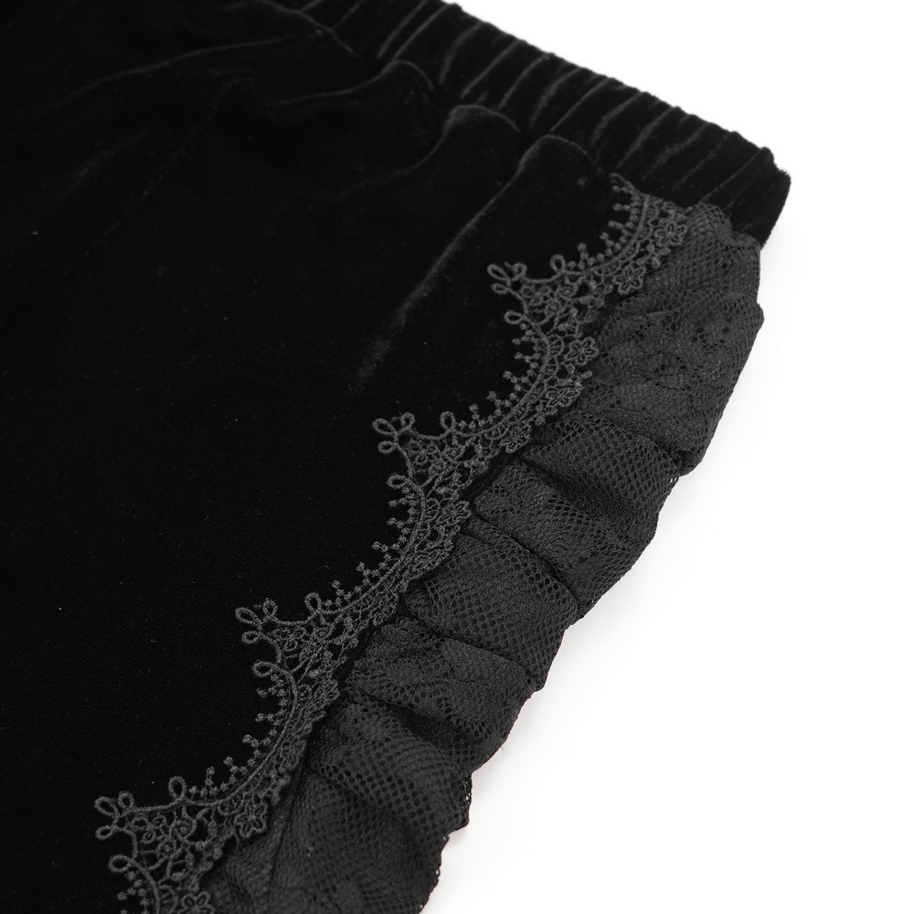 Close-up of gothic black velvet pant hem featuring intricate baroque lace detailing and ruffled edges.