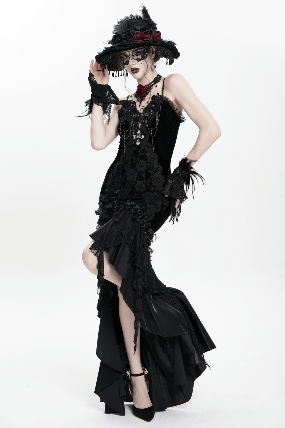 Gothic black velvet and lace high-low evening dress with ruffled hem and rose accents, worn by a model in dramatic pose.