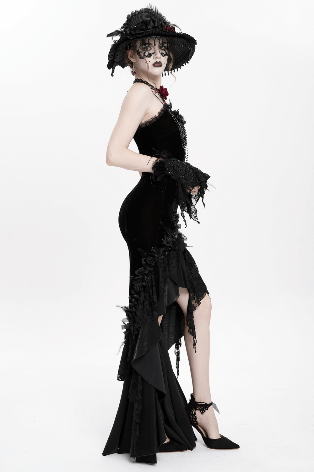 Gothic black velvet and lace high-low evening dress with floral details and dramatic ruffled hem, styled with accessories.