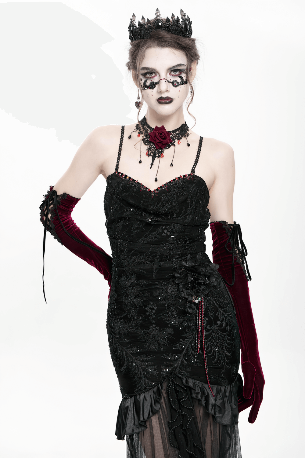 Model wearing a Gothic black velvet high-low dress with beadwork and sheer mesh, styled with dramatic accessories.