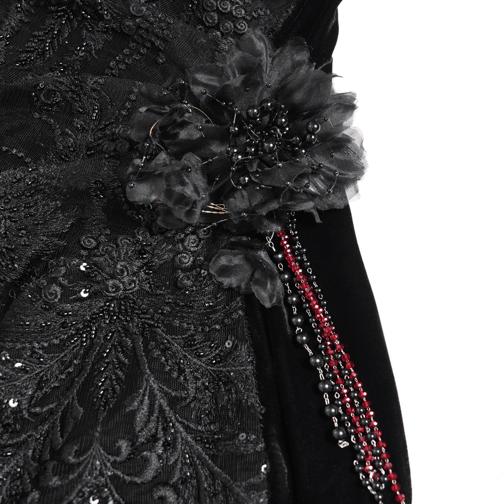 Close-up of intricate black embroidery, beaded accents, and a floral embellishment on a gothic evening gown.