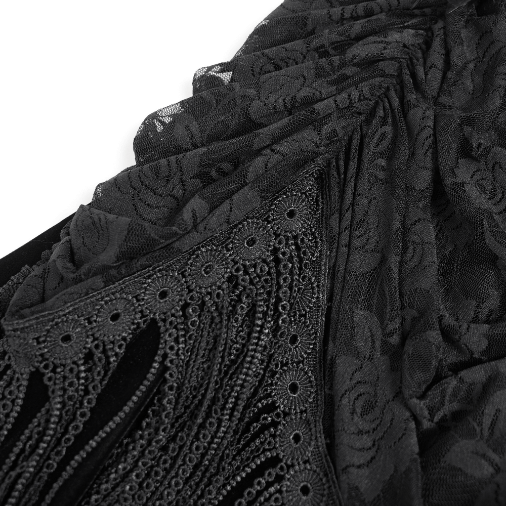 Close-up of gothic black velvet dress with lace and fringe details, showcasing intricate floral lace appliqué.