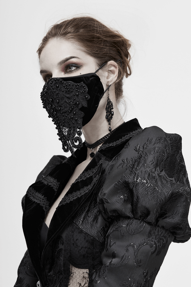 Elegant woman wearing a gothic black velvet mask with lace details, complemented by a stylish black outfit.
