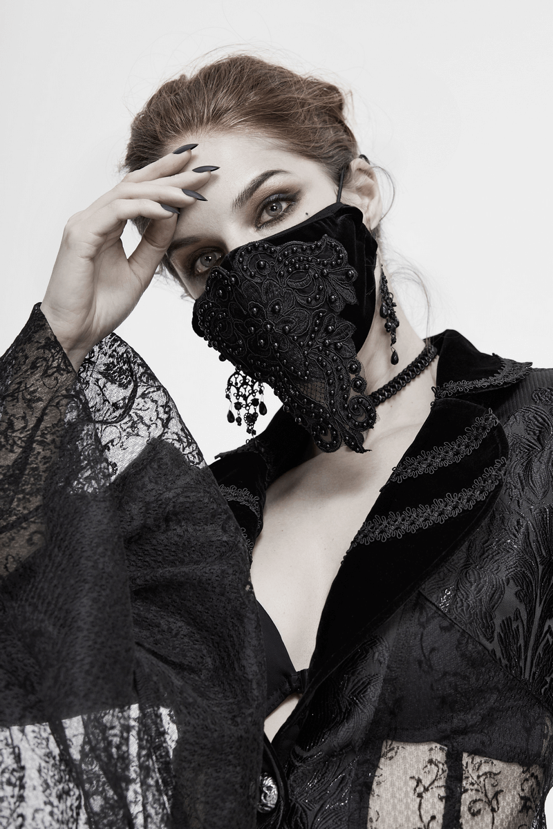 Gothic black velvet face mask with lace and bead detailing, worn by a model in a stylish black outfit.