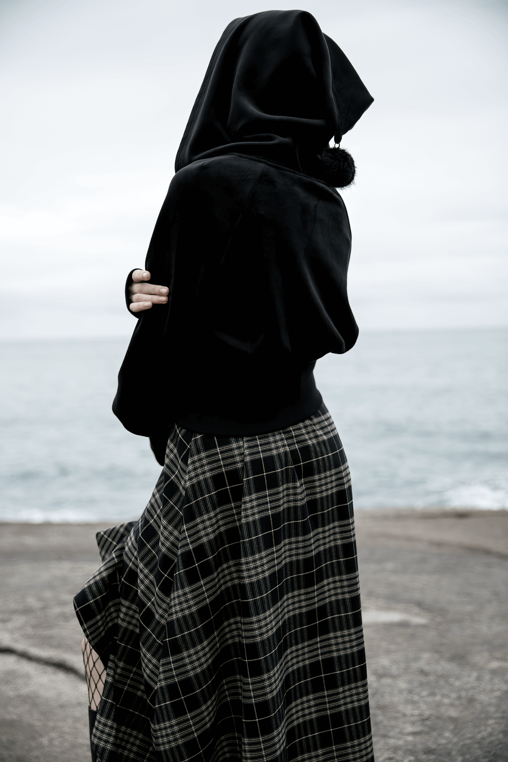 Gothic black velvet hoodie with pointed wizard hood and plaid skirt by the sea.