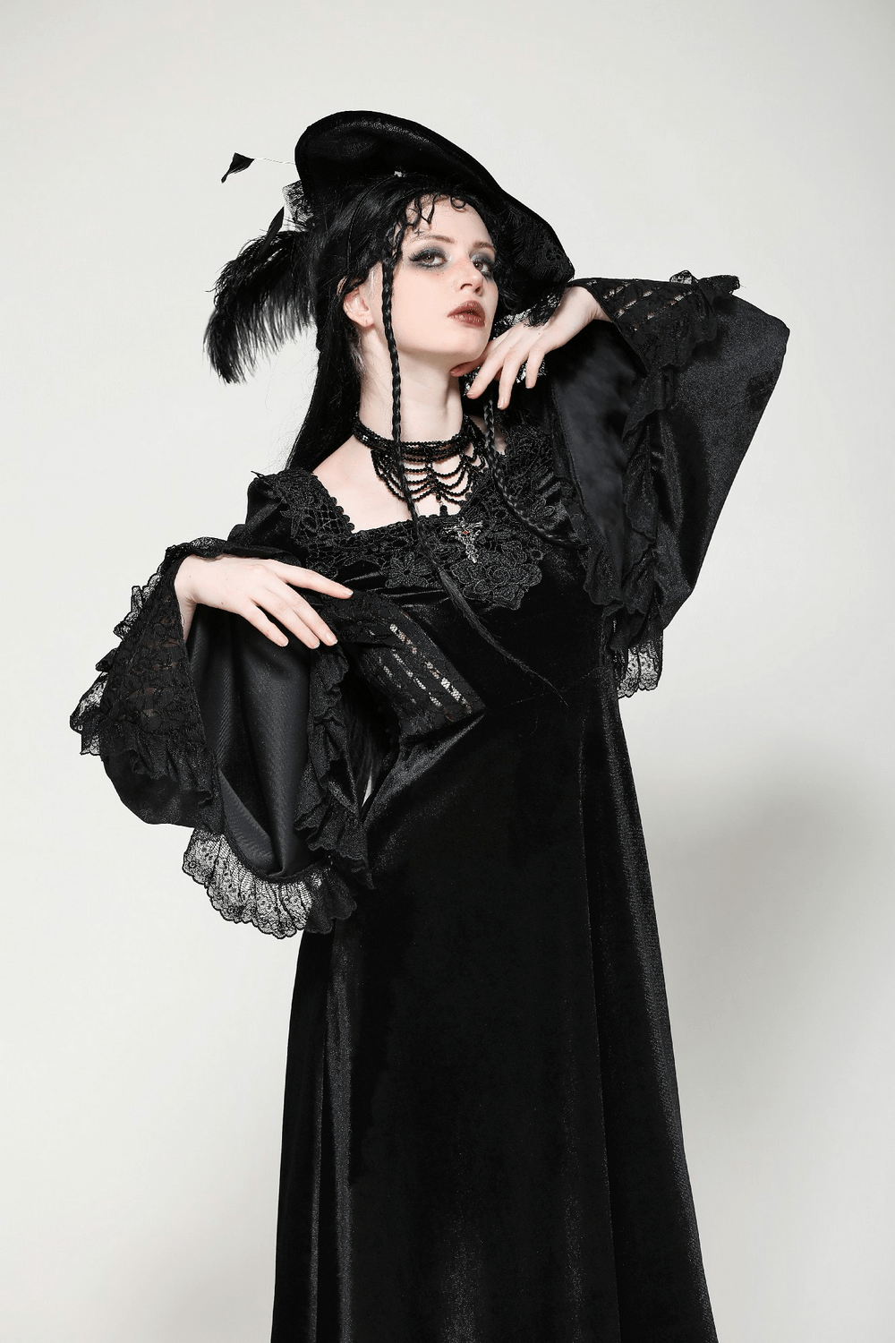 Elegant model in black velvet lace-up Renaissance dress with bell sleeves and gothic accessories, exuding gothic charm.