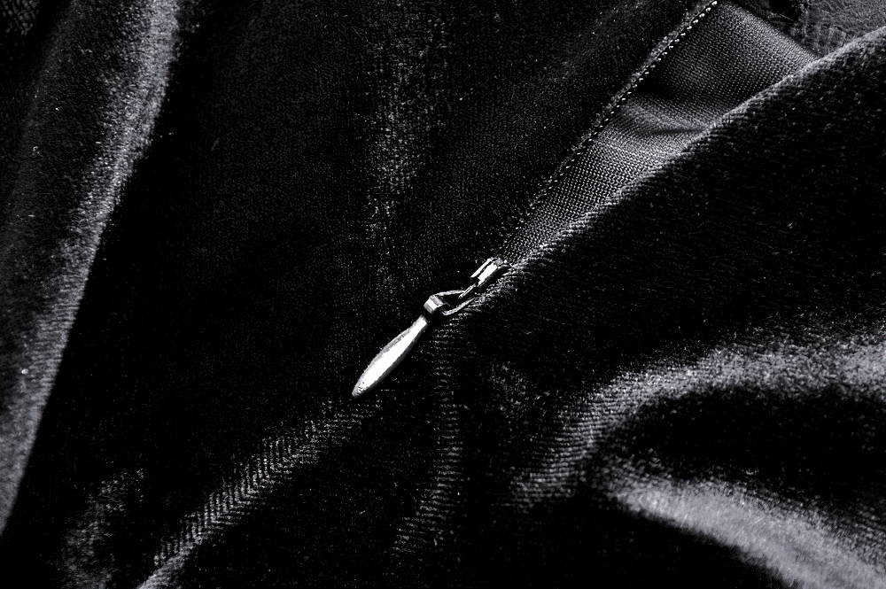 Close-up of black velvet fabric with a zipper, showcasing luxurious texture and quality for gothic fashion.