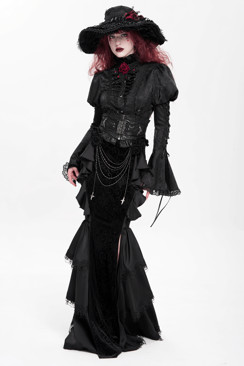 Gothic black velvet maxi skirt with ruffles and chains, paired with an elegant black blouse and wide-brimmed hat.