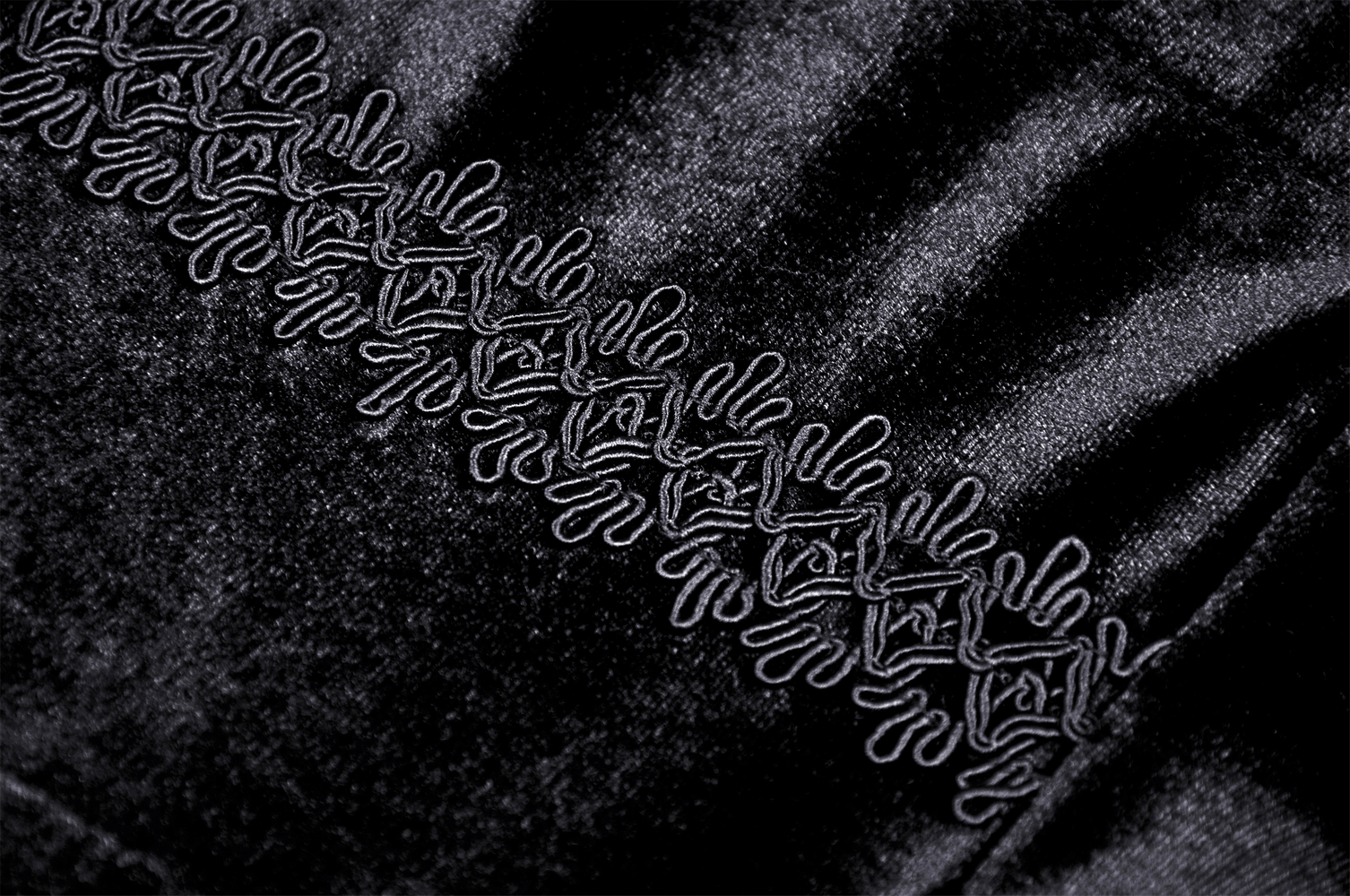 Close-up of black velvet fabric with intricate embroidery detail, perfect for gothic fashion inspiration.
