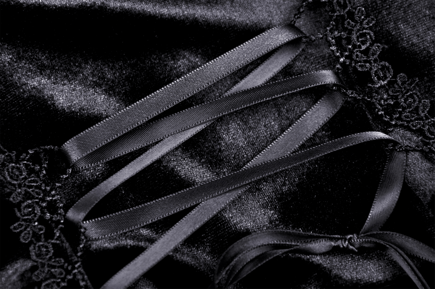 Close-up of black velvet fabric with satin ribbons and lace detailing, perfect for a gothic puff sleeve top.