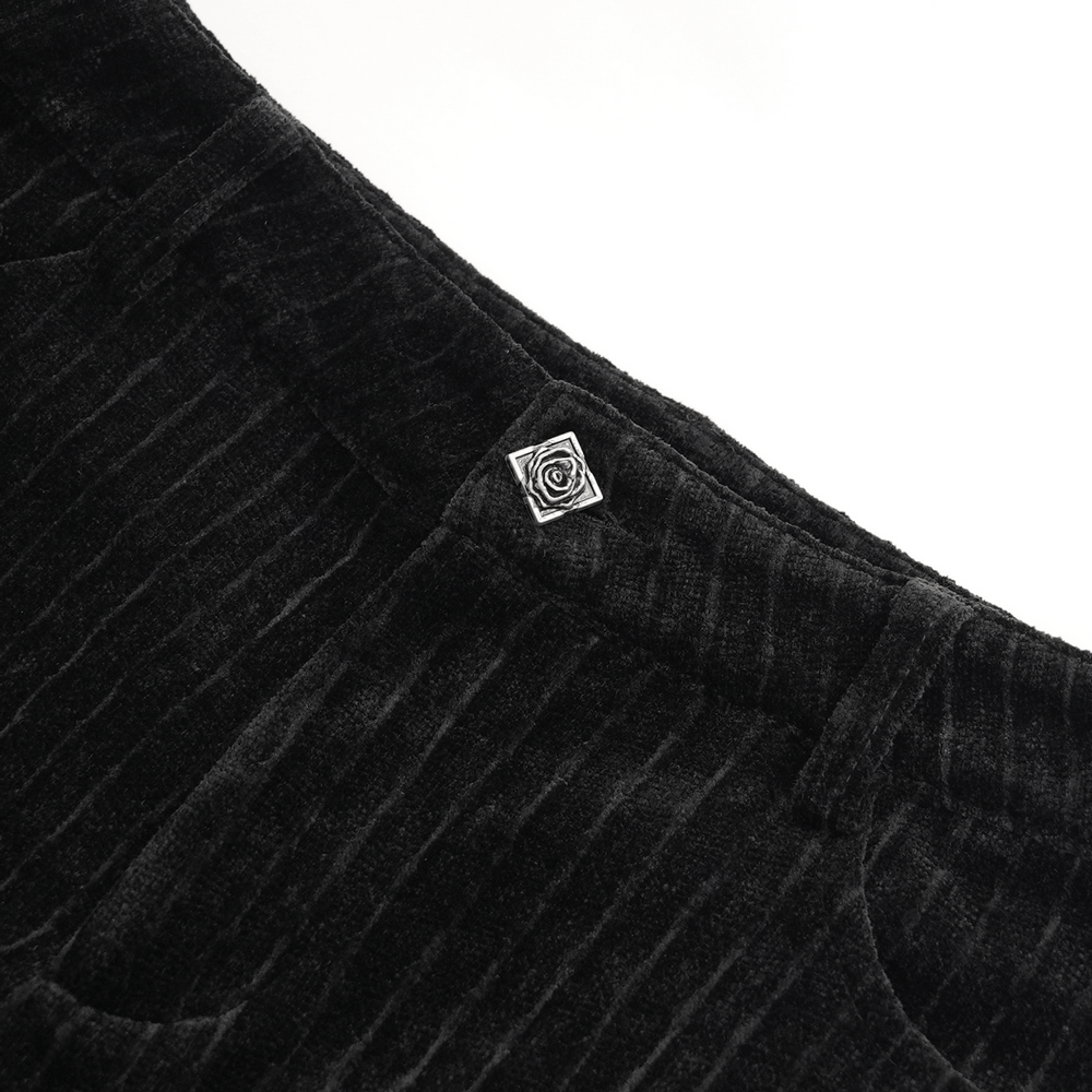 Close-up of Gothic black velvet pants featuring a decorative silver rose emblem on the waistband.