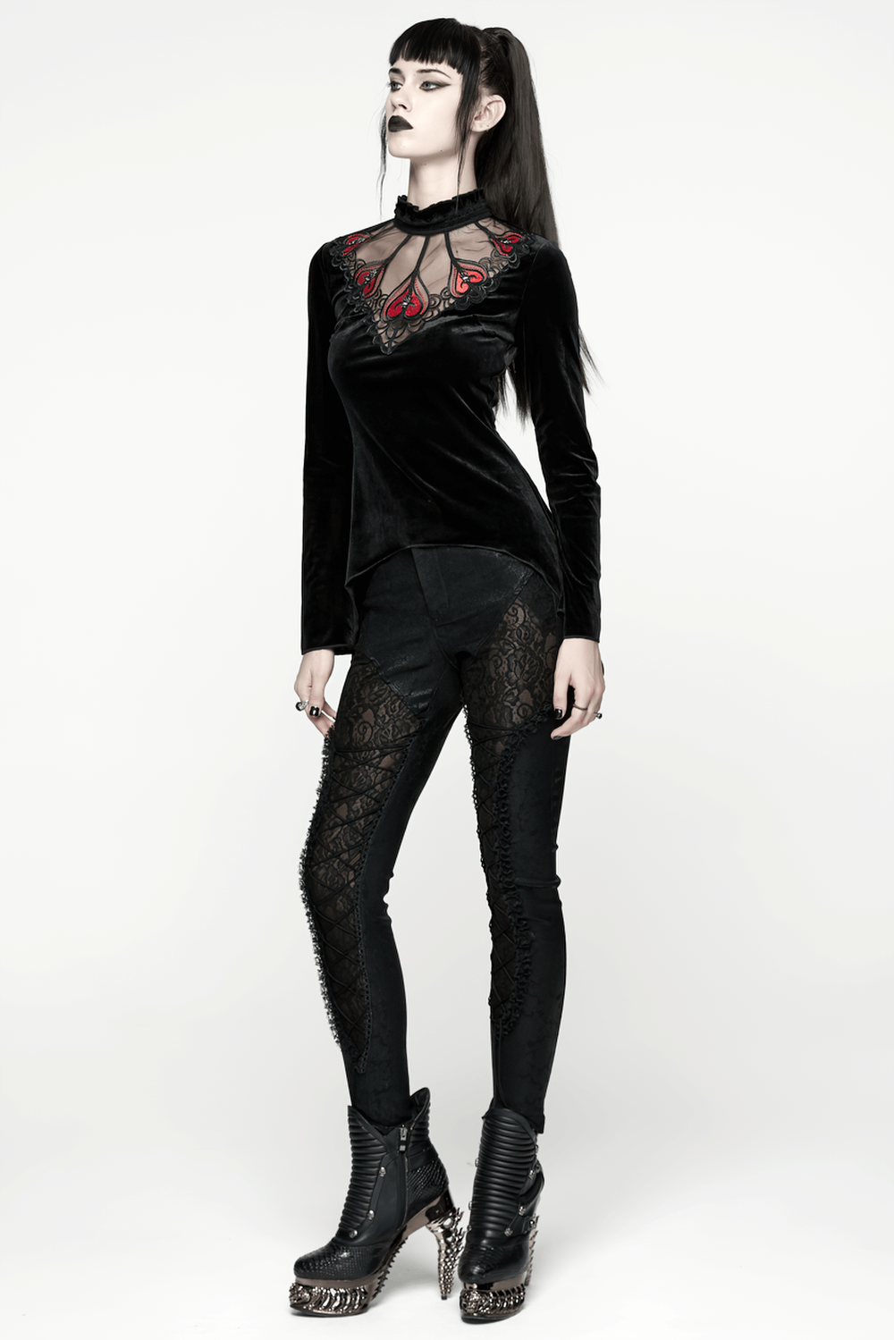 Gothic Black Velvet Top with Lace and Red Heart Detail is showcased by a model, featuring a ruffled collar and striking silhouette.