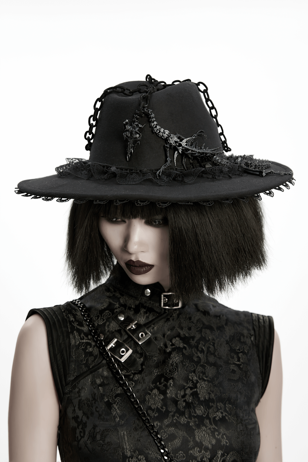 Gothic Black Wide Brim Hat with Dragon Bone Chains on a model with dark makeup and Victorian style attire.