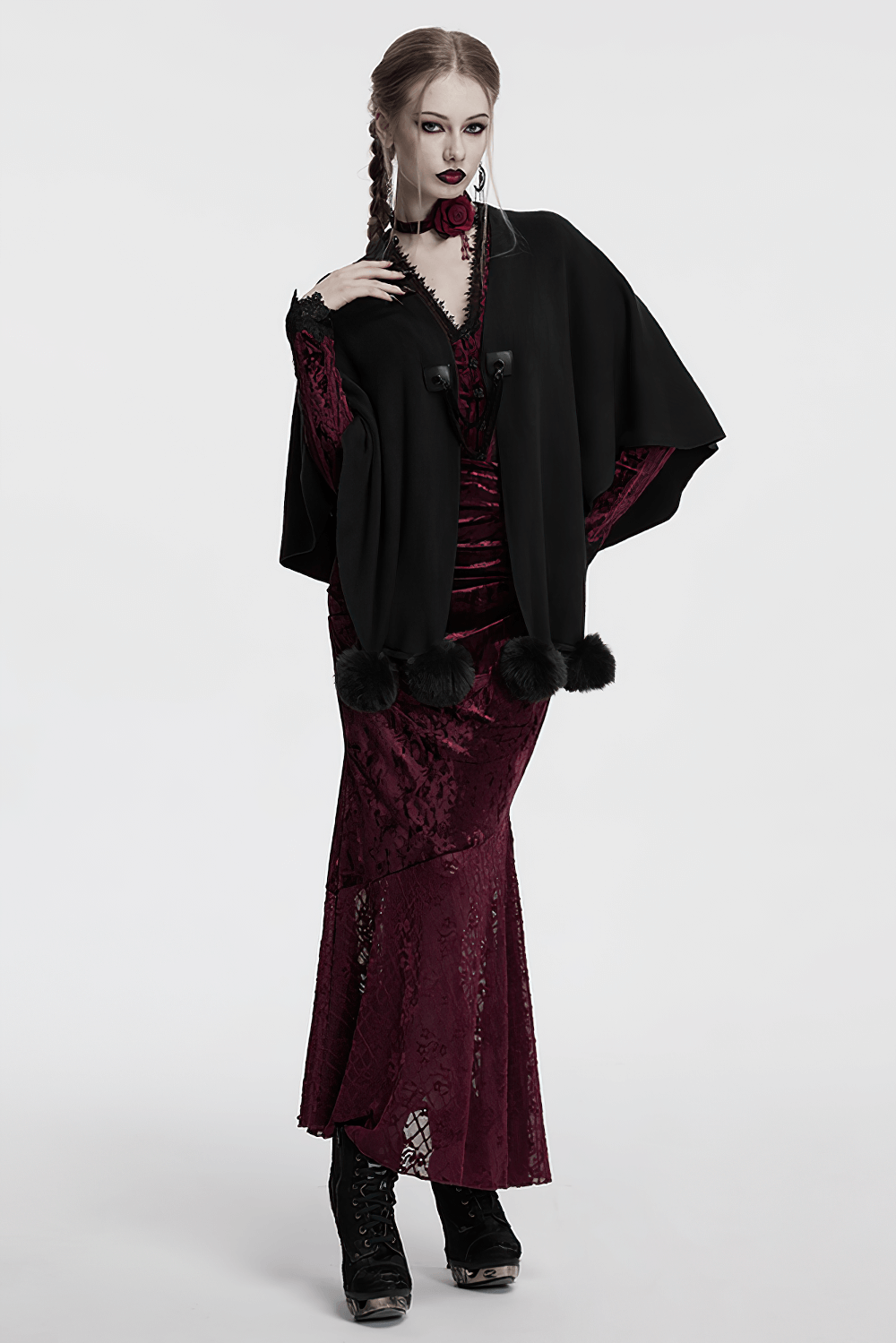 Gothic black woolen shawl with fur ball trim layered over a burgundy lace dress, exuding witchy elegance.