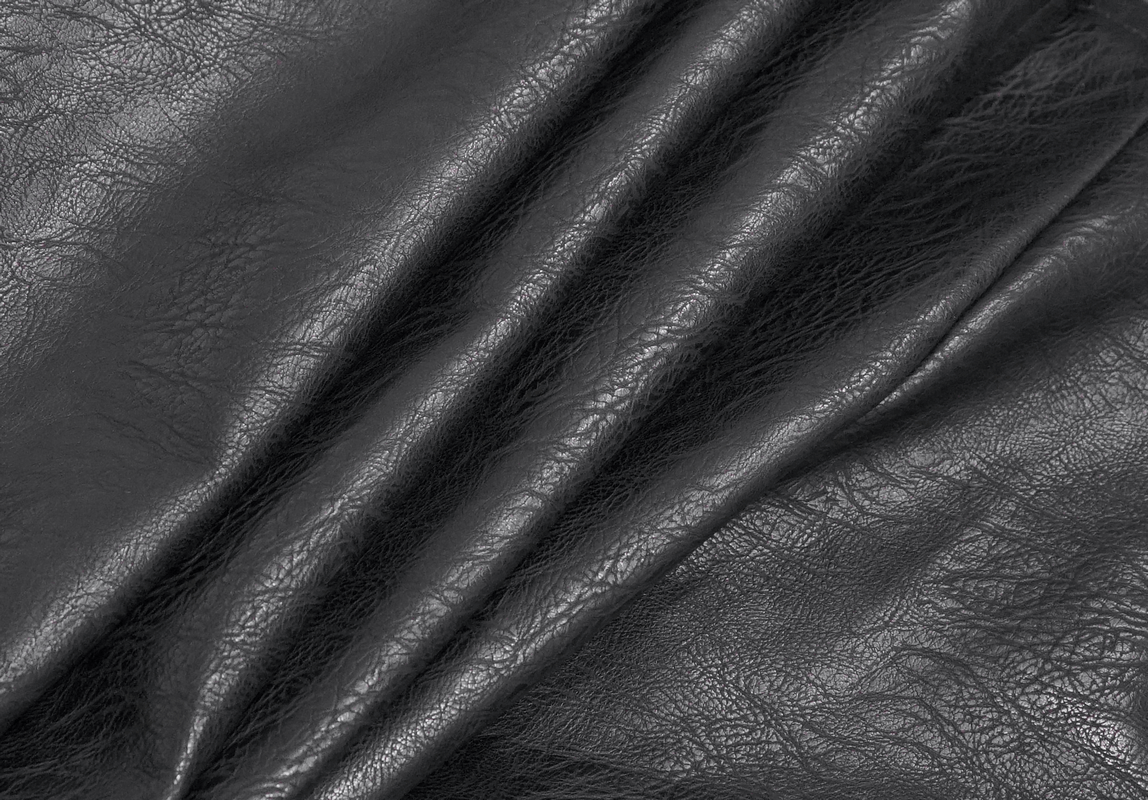 Close-up of textured black PU leather fabric, perfect for a gothic style coat.