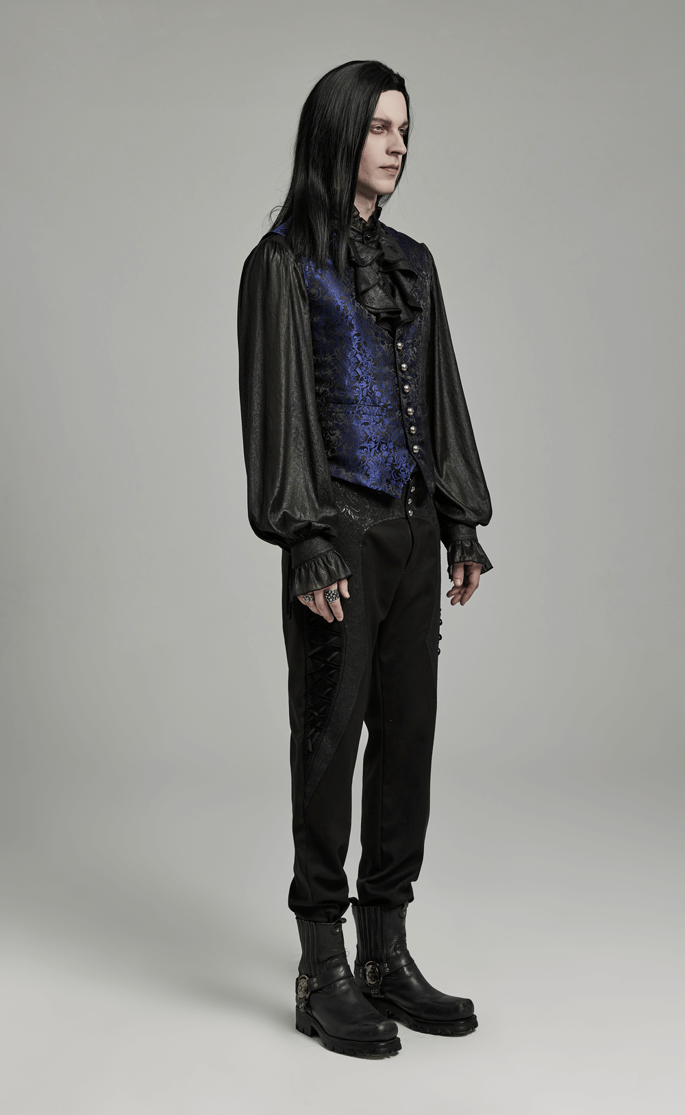 Stylish man in Gothic brocade waistcoat with leather detail and black pants, showcasing elegant gothic fashion.