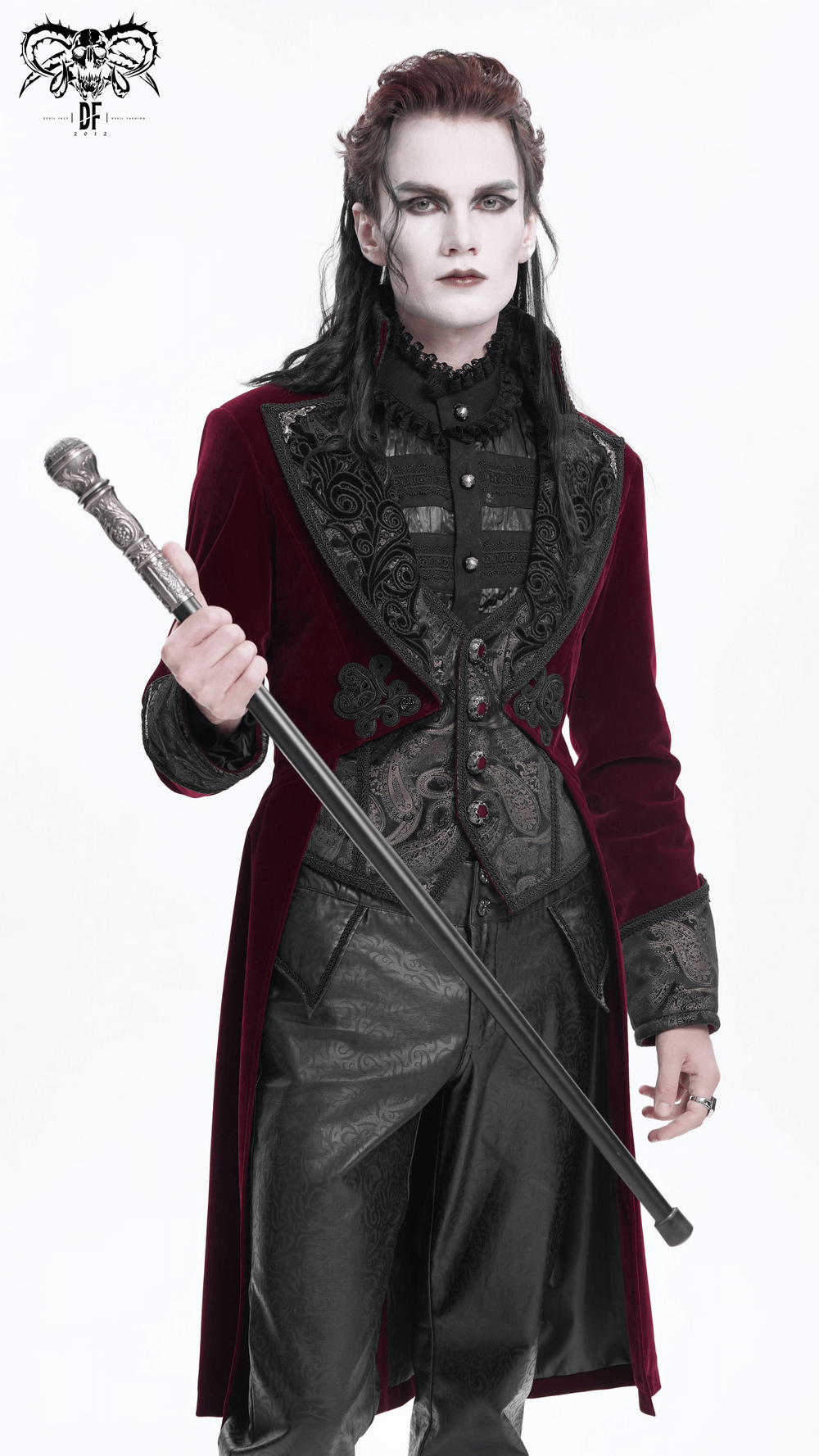 Man in a gothic burgundy velvet tailcoat with embossed accents and a stylish cane, exuding Victorian elegance.