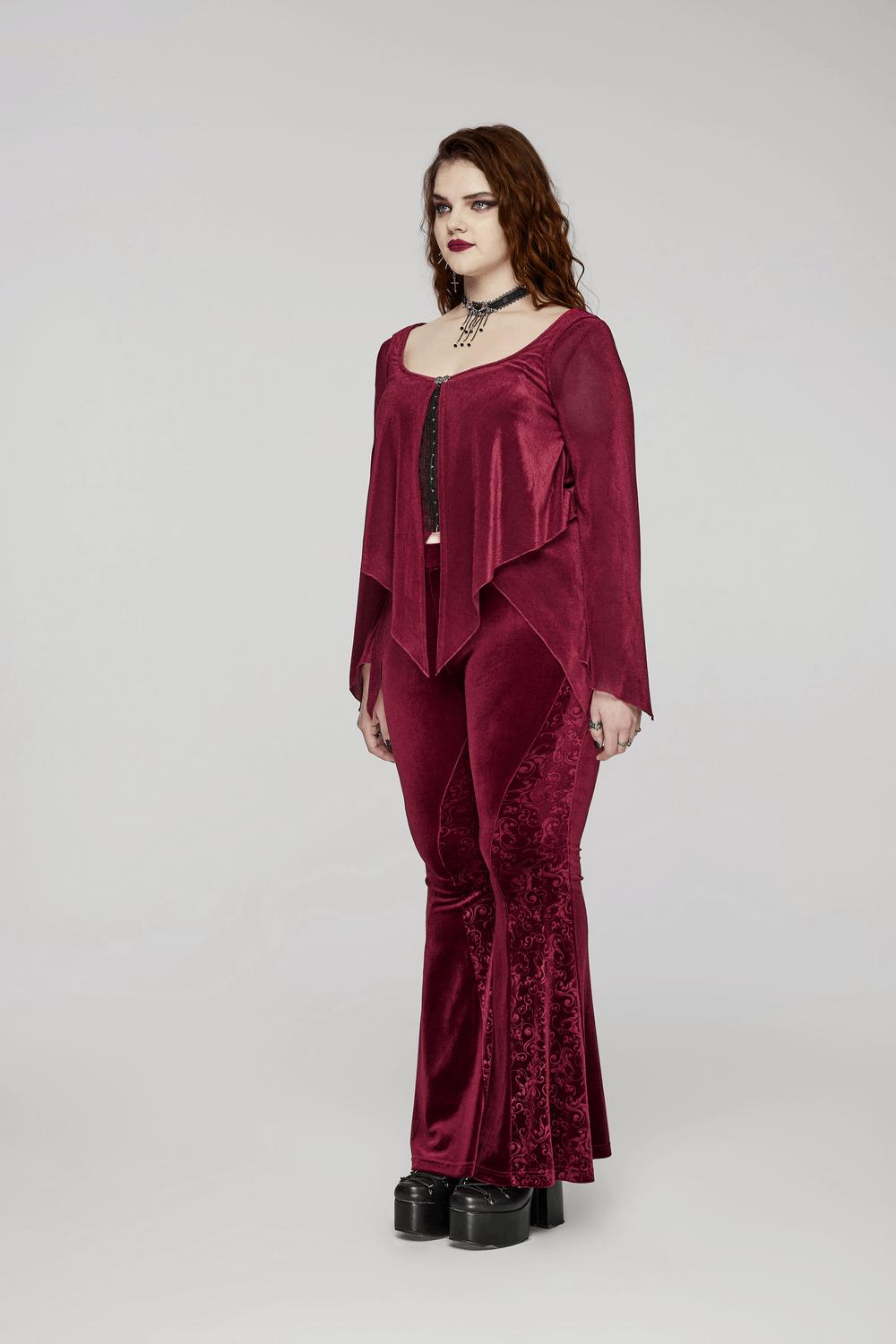 Model showcasing elegant gothic burgundy velvet flared pants with embossed details and stylish top.