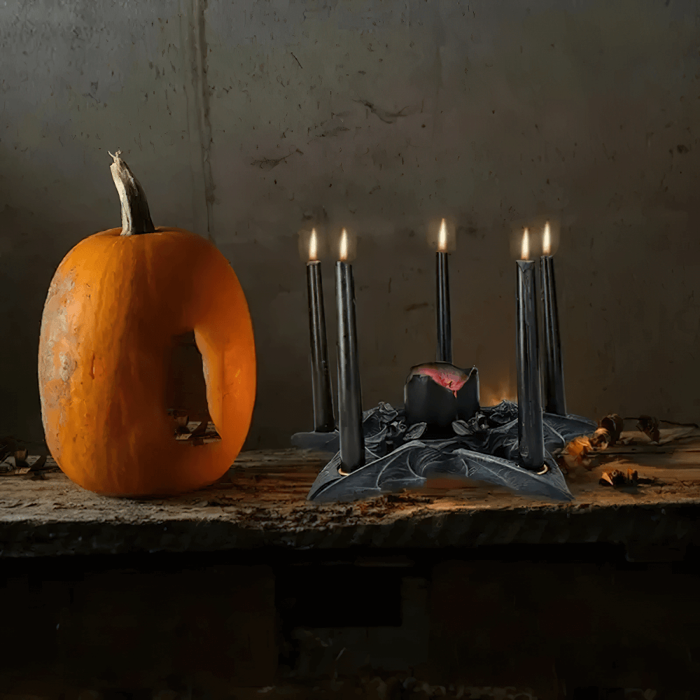 Gothic bat candle holder with black candles alongside a spooky carved pumpkin for Halloween decor.