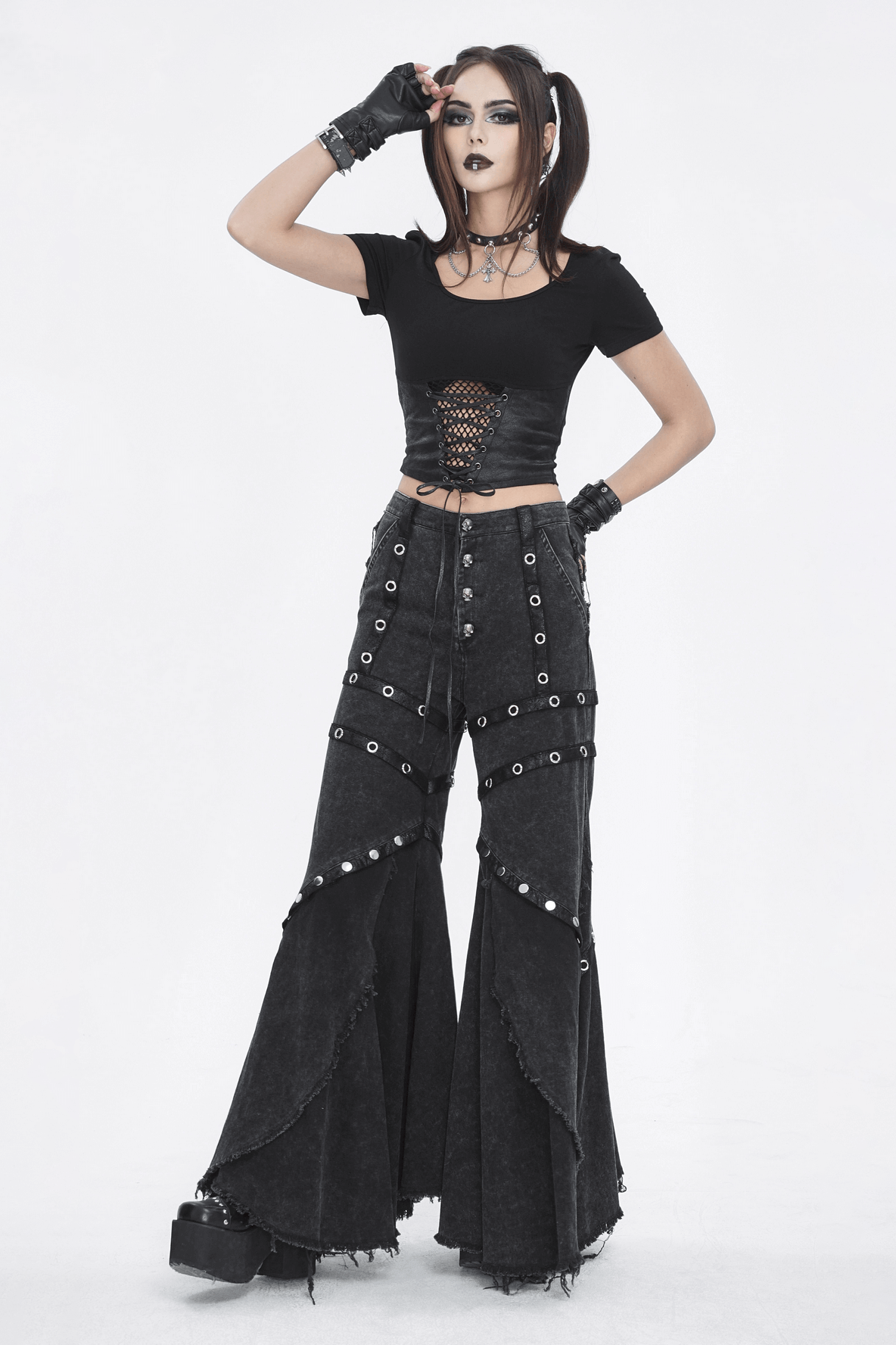 Model in black gothic crop top and flared pants with edgy details, showcasing bold fashion style.