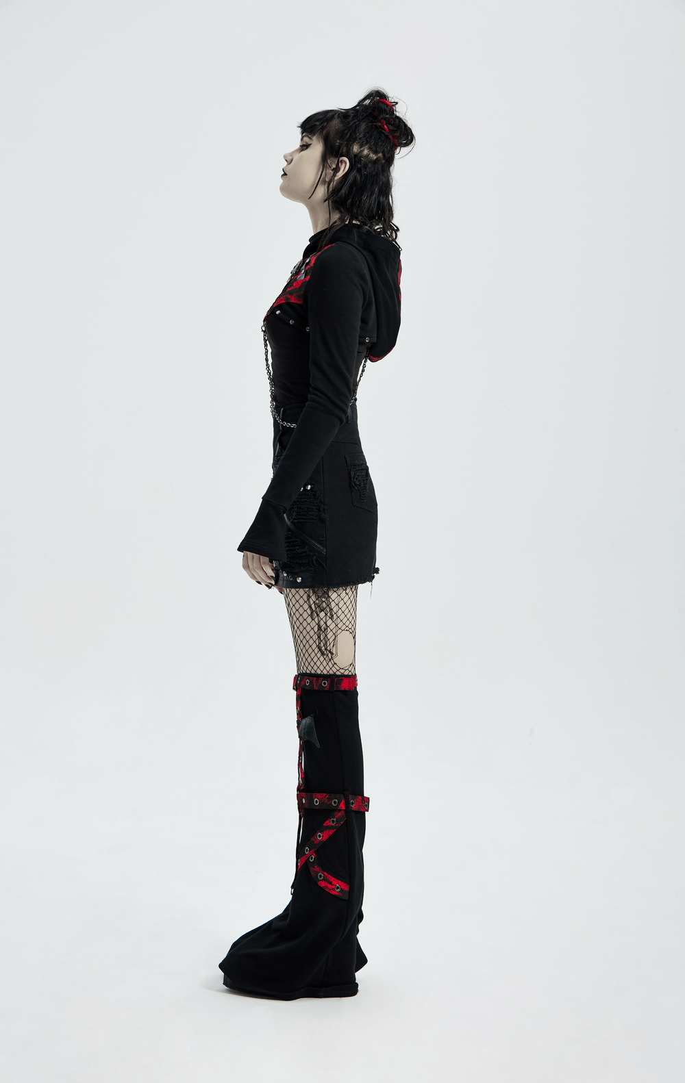 Edgy gothic model in a knitted top with chain detail and contrast hood, showcasing punk fashion style.