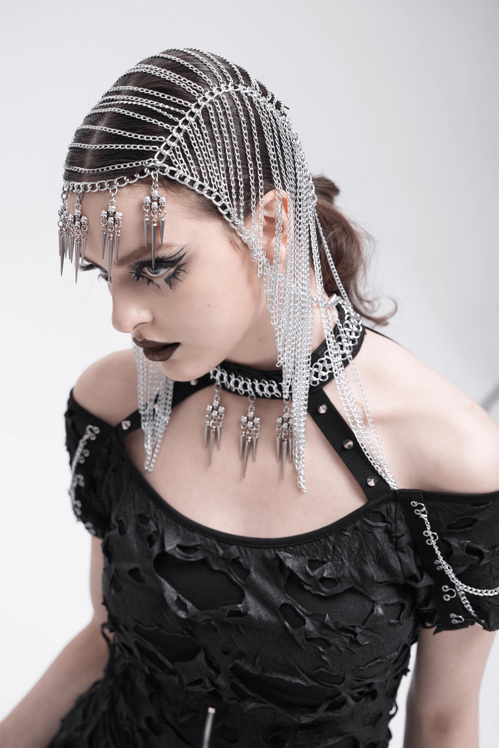 Model wearing a Gothic chain headpiece with spiked skull dangles, styled with punk clothing and dramatic makeup.