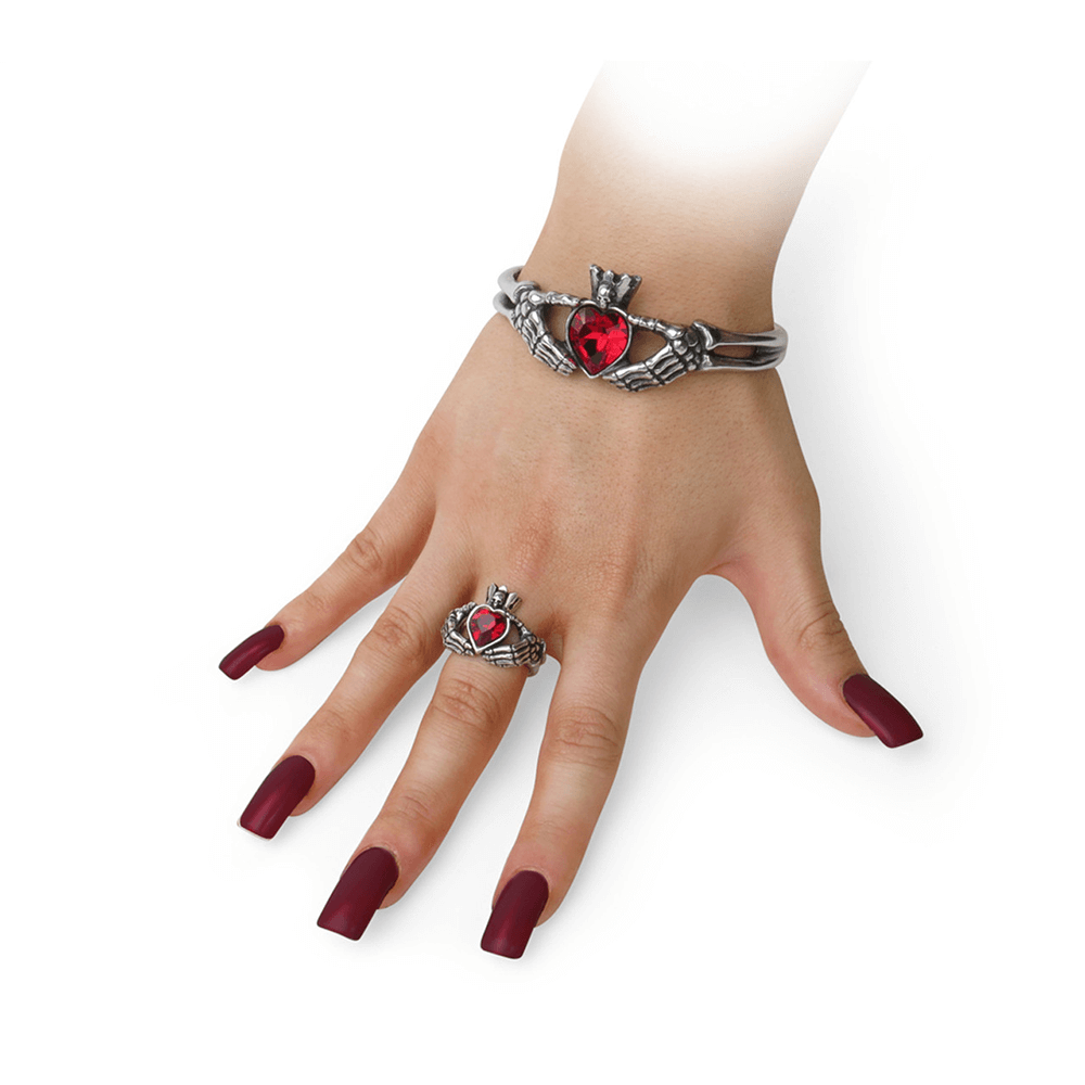 Gothic Claddagh ring with red crystal showcased on a hand with striking long nails and matching bracelet.