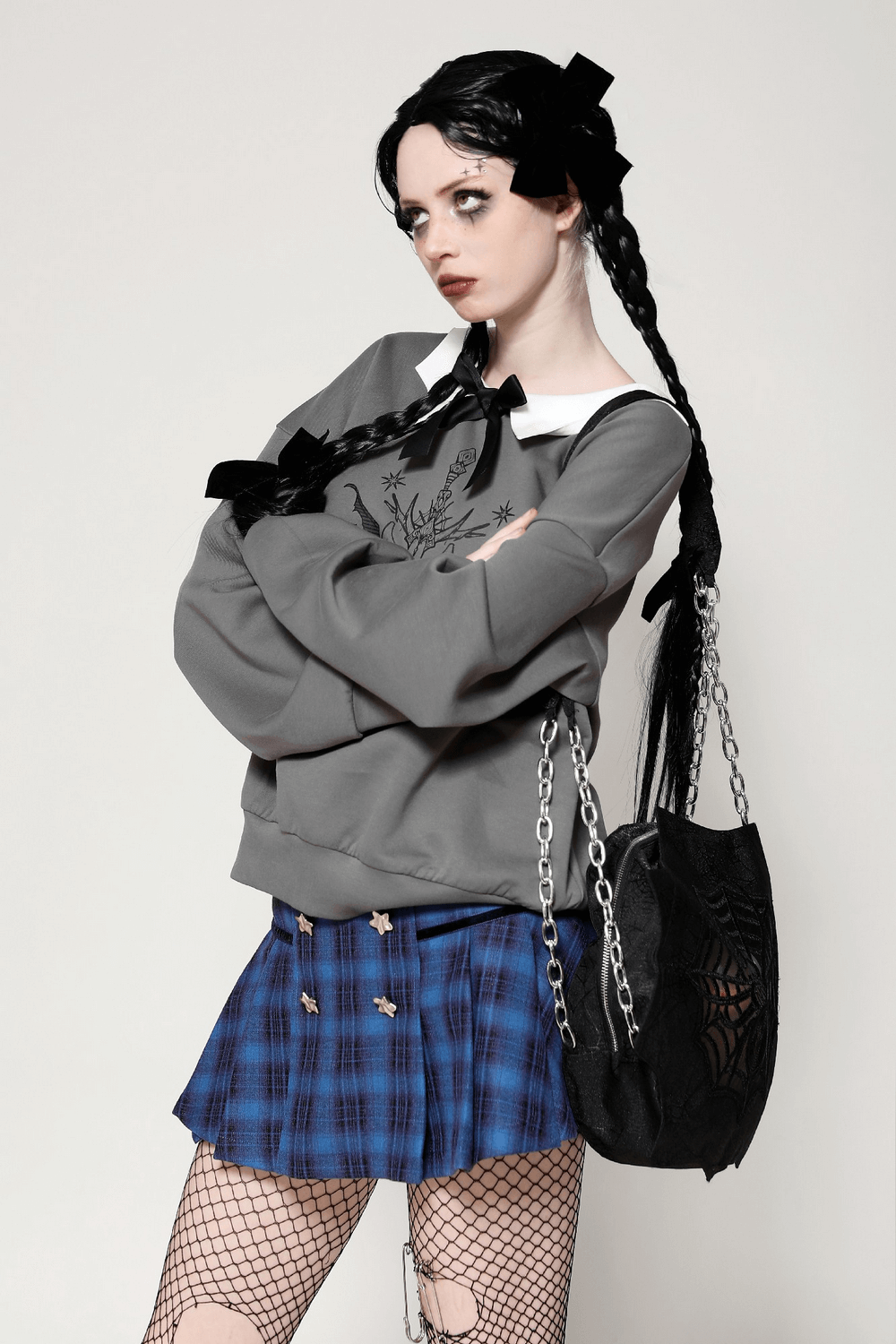 Model showcasing a gothic collar bow sweatshirt with cat design, paired with a plaid skirt and fishnet stockings.