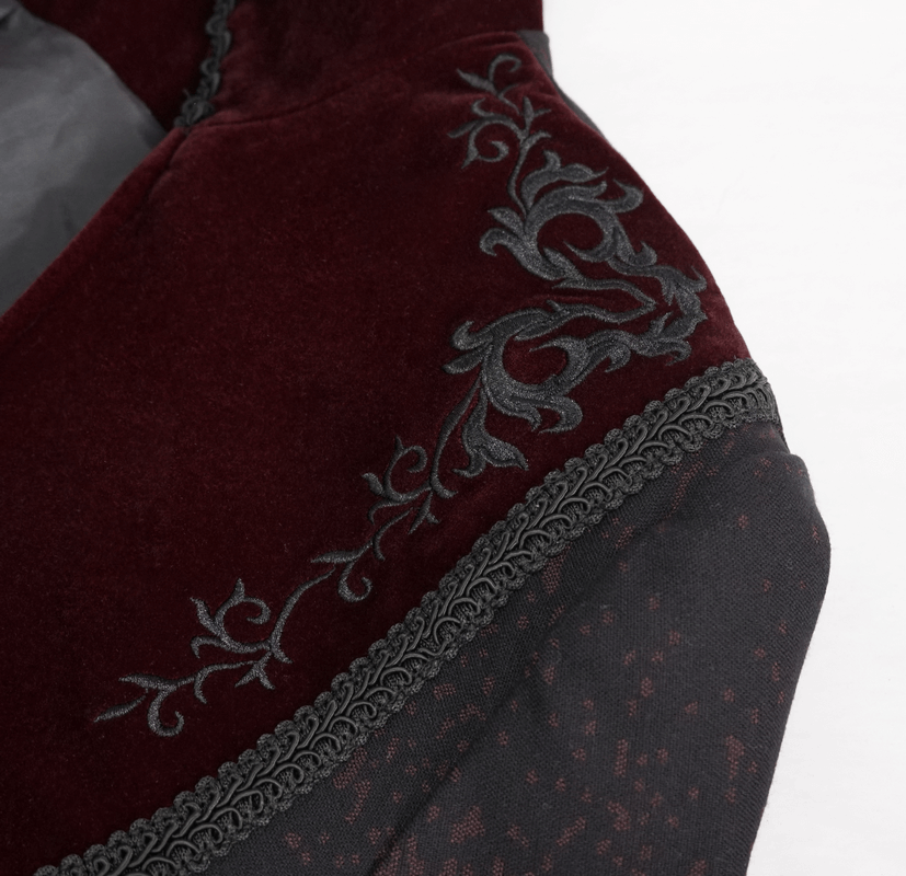 Close-up of gothic coat fabric showcasing burgundy velvet with intricate black floral embroidery.